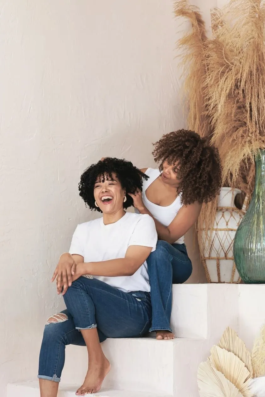 Two clients with curly and coily hair laughing at the Montreal studio